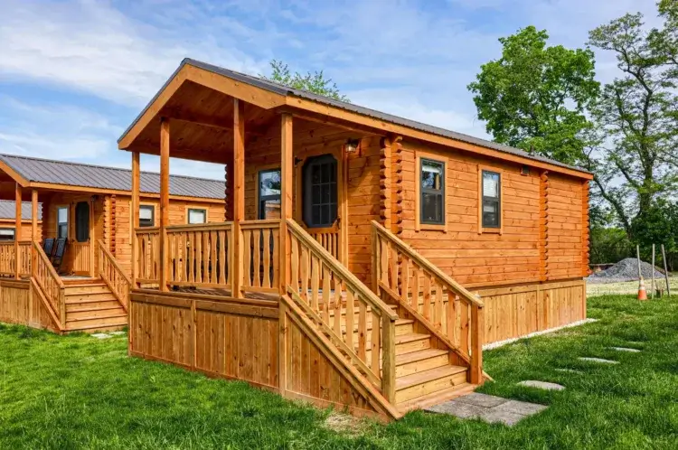 The Shenandoah modular log cabin kit in a clean park-style setting with green grass.