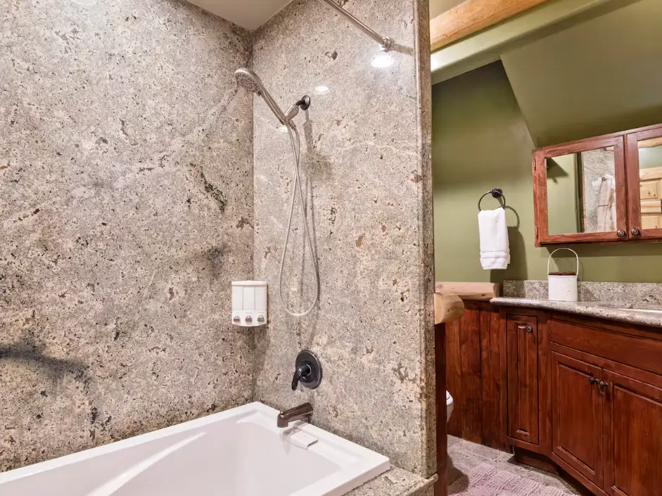 A modern spa-like bathroom in a Big Bear cabin, with a full granite-style shower and a deep soaking tub.