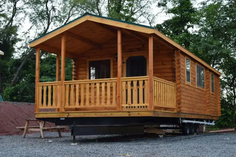The Ozark prefab log cabin kit on a frame with wheels, illustrating its delivery method.