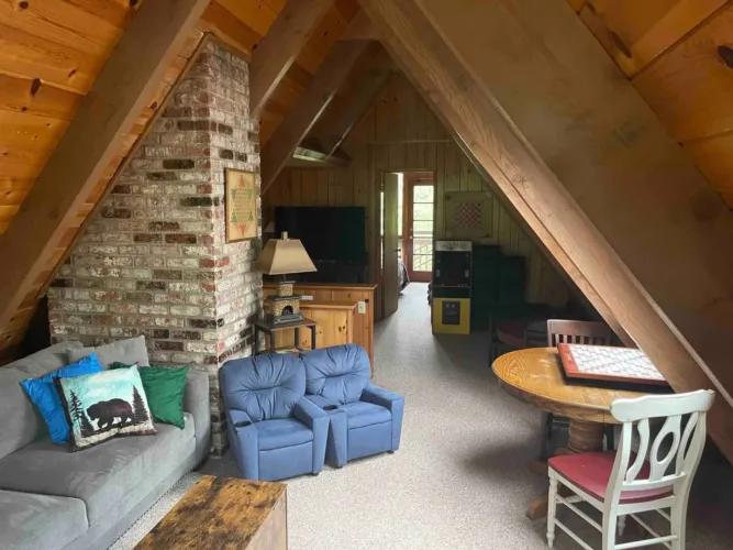 Traditional simple A-frame house interior of 'Dillard House Chalets' featuring a brick chimney and wood paneling.