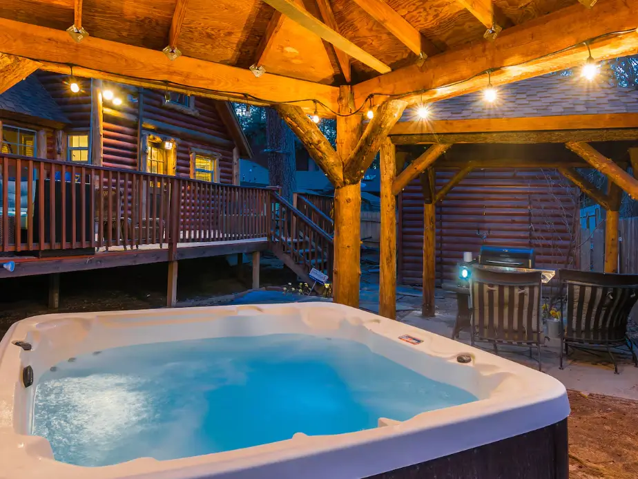 A steaming private hot tub at a Big Bear cabin, illuminated by string lights for a perfect evening.