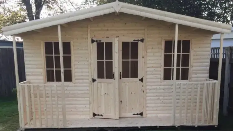 A beautiful, newly built shed log cabin made from natural pine, featuring a full-length covered porch with railings.