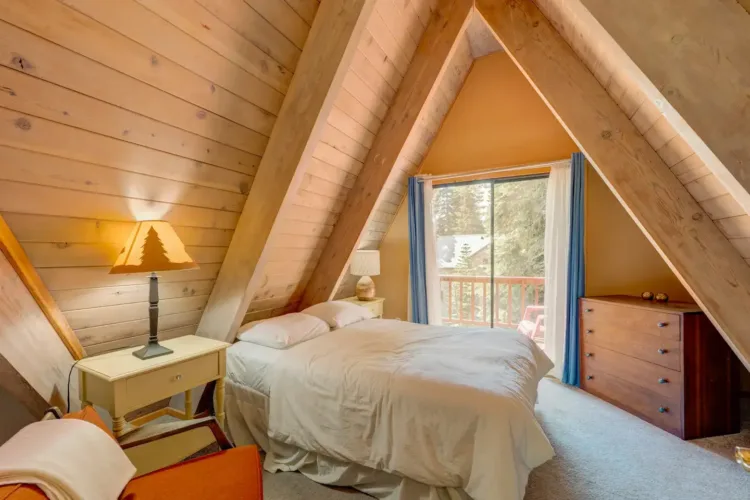 Cozy A-frame cabin bedroom ('Relaxation on Muletail') with light wood paneling and view to a balcony.