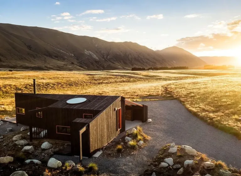 Minimalist Scandinavian-inspired Skylark Cabin set in a vast New Zealand landscape at sunrise, showcasing Nordic design principles of harmony with nature.