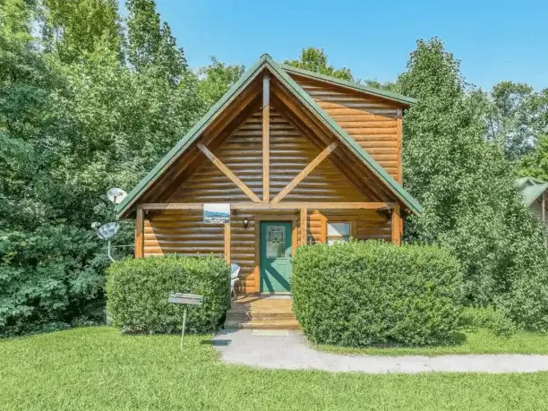 Inviting small secluded log cabin in Gatlinburg, TN, nestled in green trees, perfect for a mountain getaway.