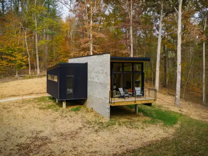 An angled, wide shot of the Plahaus Cabin, showing how the modern structure is situated on a hillside in the woods.