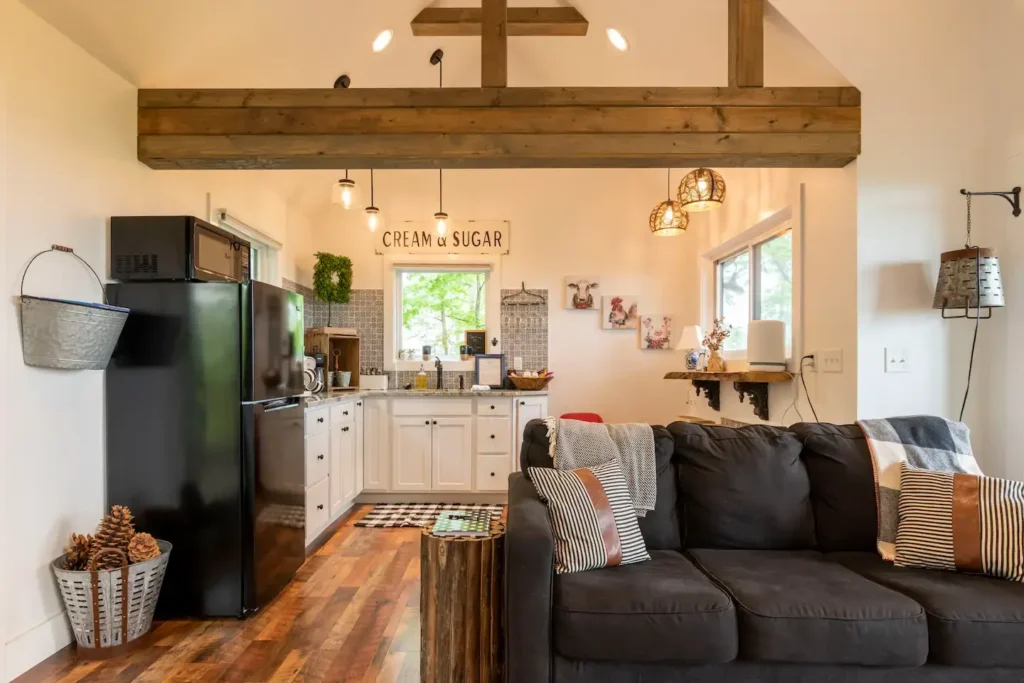 The open-plan living space in the Asheville treehouse, highlighting the rustic exposed wood beam that separates the living room and kitchen areas.