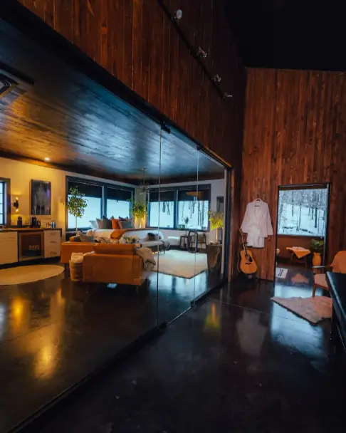 The open-concept interior of the Birch Falls Spa Cabin, showing the seamless flow between the living area and the bedroom with warm wood accents.