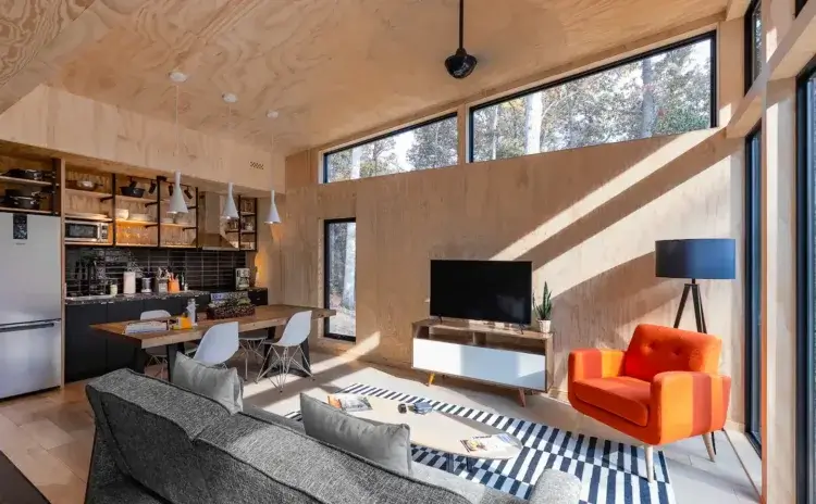 The open-plan living area of the Modern Nashville Home, showing the kitchen with black tile, dining table, and living room with a bright orange chair.