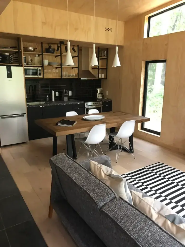 A close-up of the modern kitchen and dining area in the Plahaus tiny house retreat, showing the sleek black cabinetry and wood dining table.