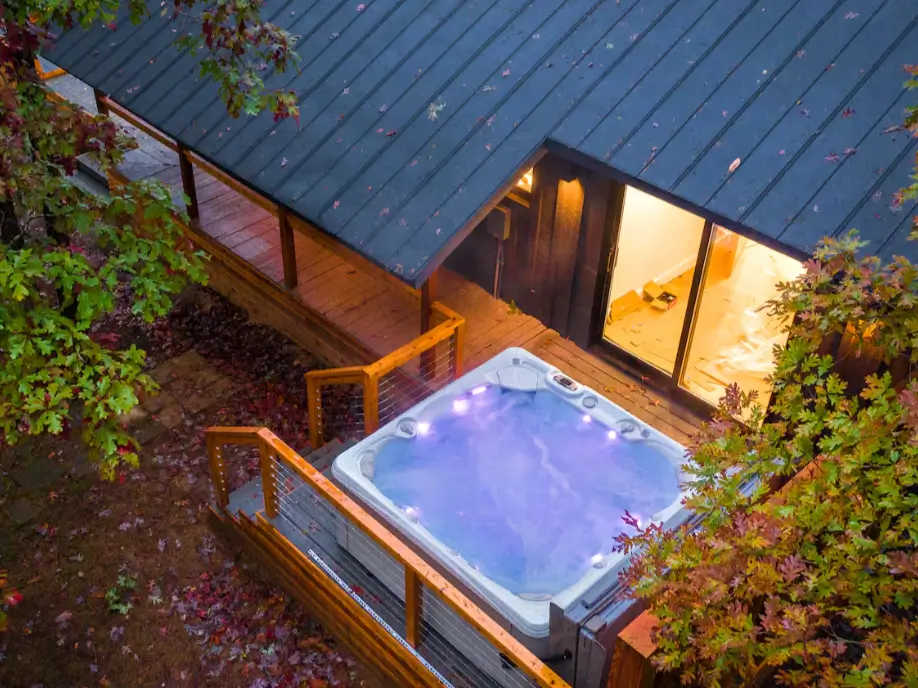 The private, glowing hot tub on the wooden deck of The Coalmont cabin, viewed from above at dusk.
