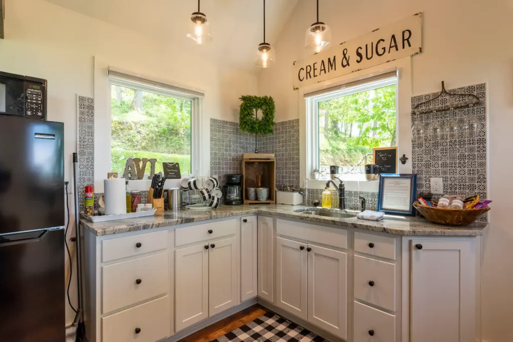The well-equipped kitchen in the modern farmhouse treehouse, featuring white shaker cabinets, a coffee station, and stylish patterned tile.