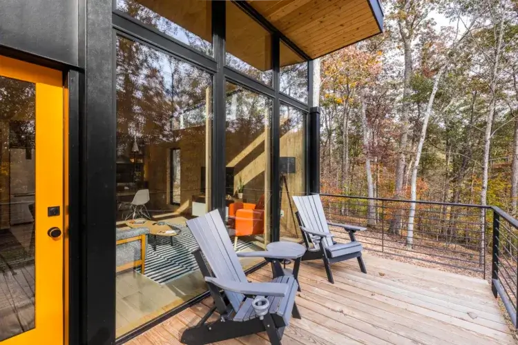 View from the Plahaus Cabin's wooden deck with two chairs, looking out into the dense autumn forest of Brown County, Indiana.