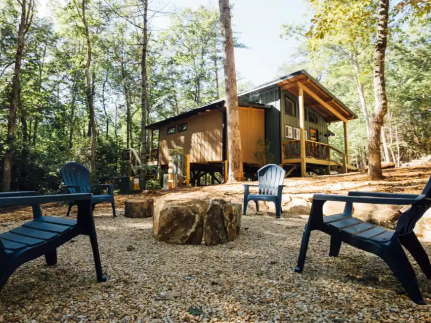 The cozy fire pit area at the Trahlyta cabin, surrounded by chairs in a wooded setting.