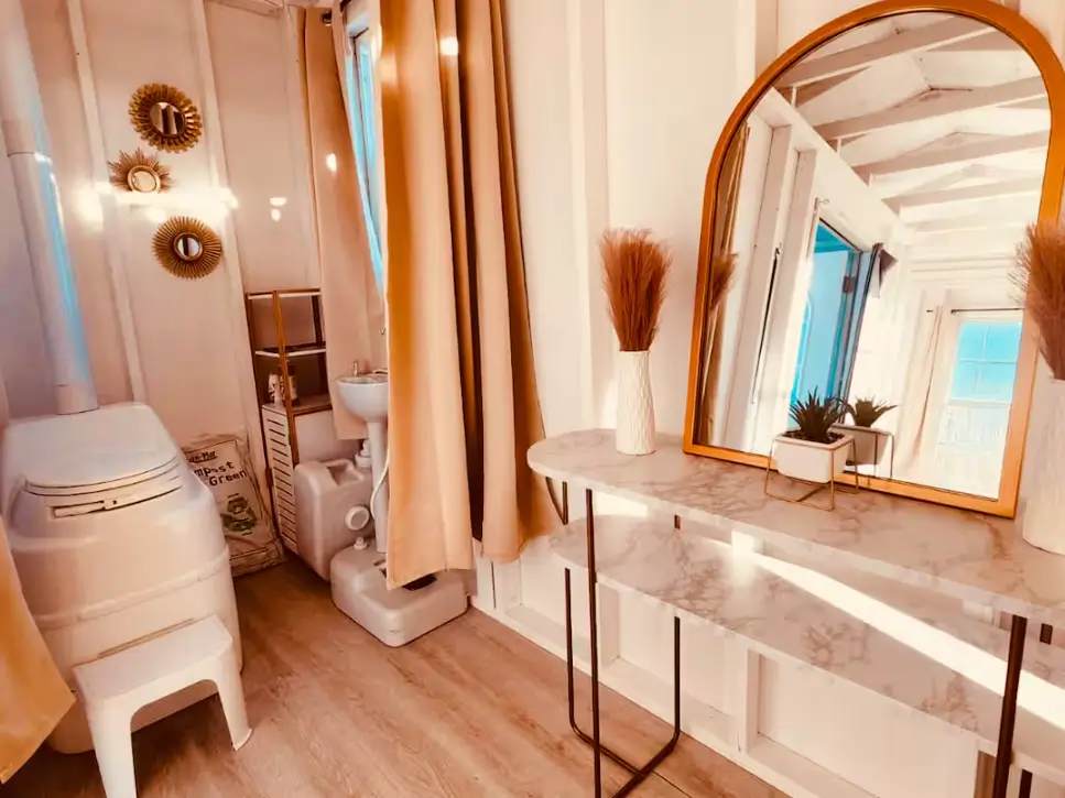 A complete off-grid bathroom in a one bedroom tiny house, featuring a composting toilet and a compact sink system.