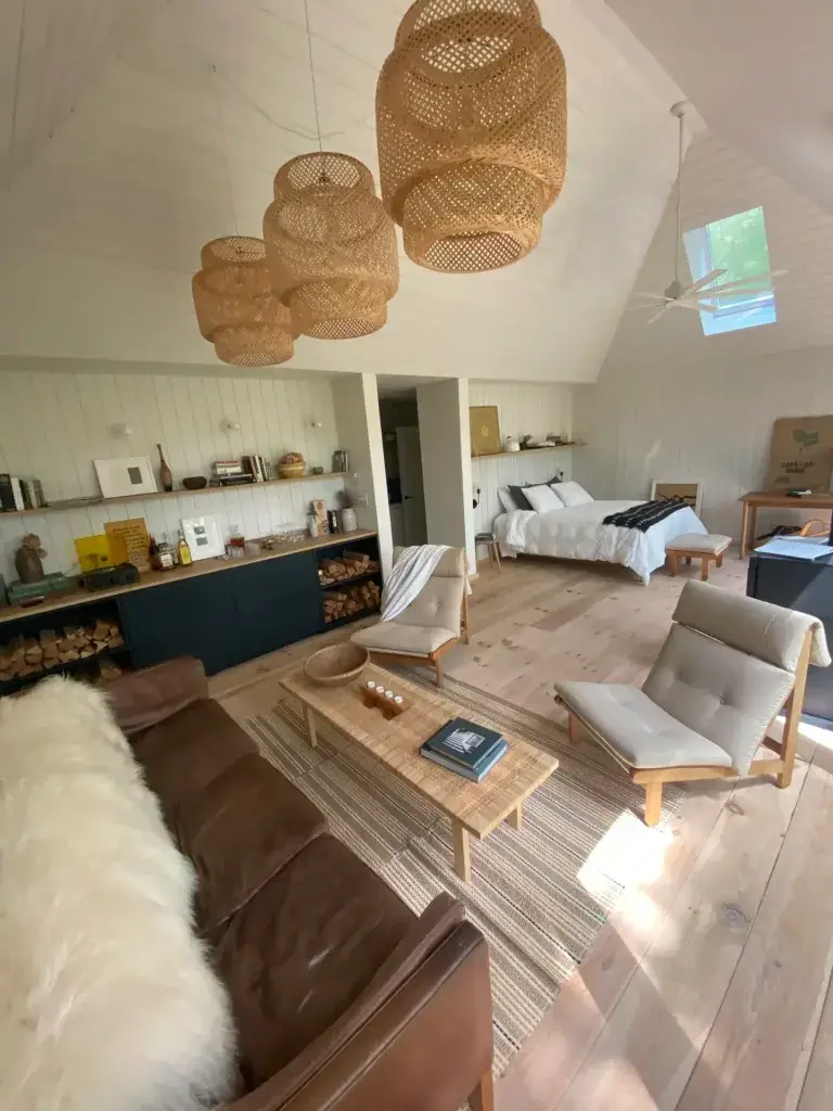 Wide-angle interior view of a 600 sq ft tiny house showing the open-concept living room, kitchen, and bedroom area under a vaulted ceiling.