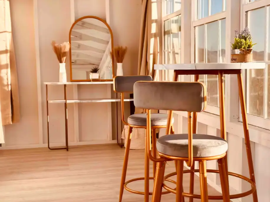 The stylish interior of a one bedroom tiny house, featuring a high-top dining table and modern decor that maximizes space and light.