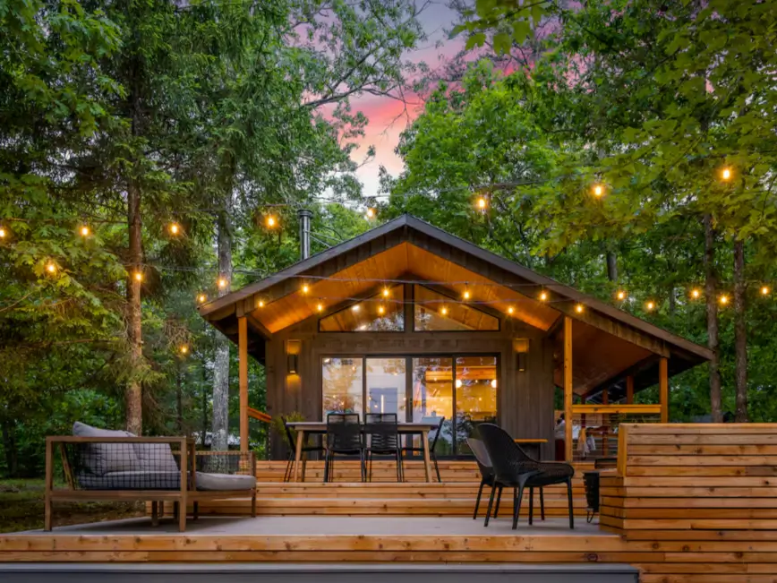 The modern exterior of The Coalmont cabin at sunset, with glowing string lights over the deck and seating area.
