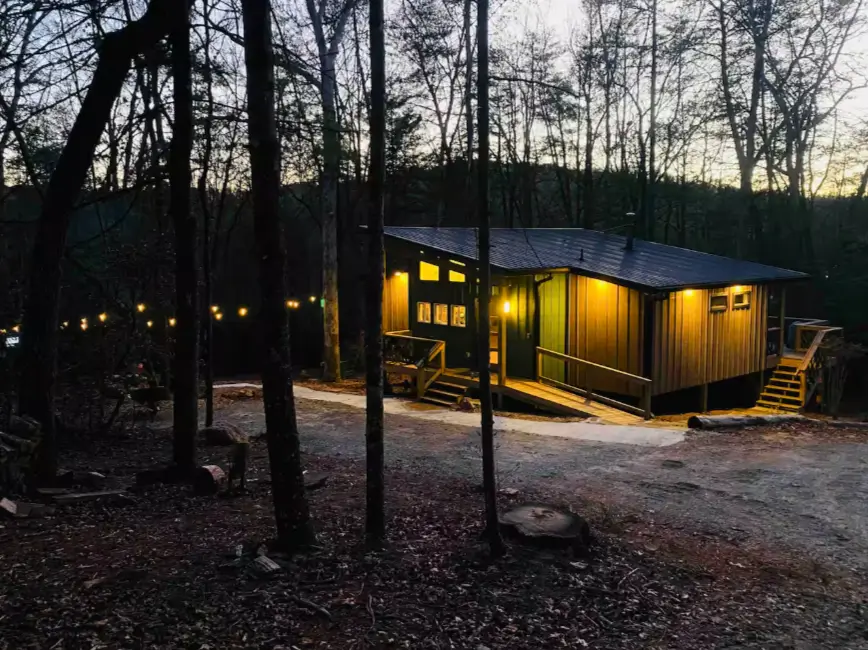 The Trahlyta cabin lit up at dusk, creating a warm and inviting atmosphere in the woods.