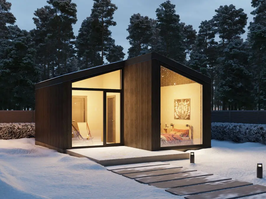 The Lund modular home, a modern prefab studio with dark siding in snow, a Scandinavian-style modular home under 50k.