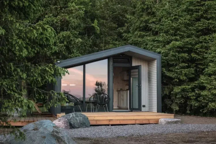The M28 micro-cabin with a full glass front, a contemporary prefab home for under 50k in a forest setting.