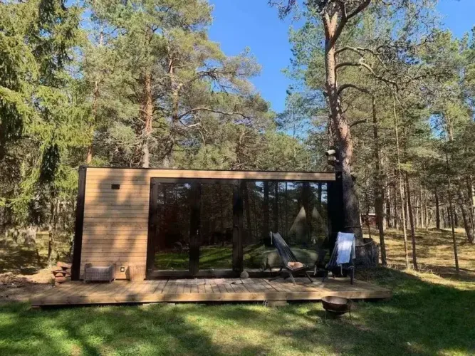 The Bliss Hut, a modern tiny home with a full glass front and wood siding, a minimalist prefab home for under 50k.
