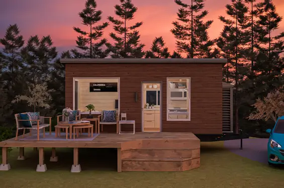 The California Studio tiny home with a wood exterior and front deck, a versatile prefab home under 50k.