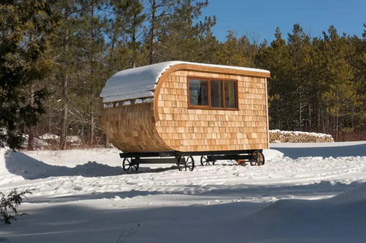 The Tobermory Shepherd Hut by Gute, fully clad in wood shingles, a rustic modular home under 50k in snow.