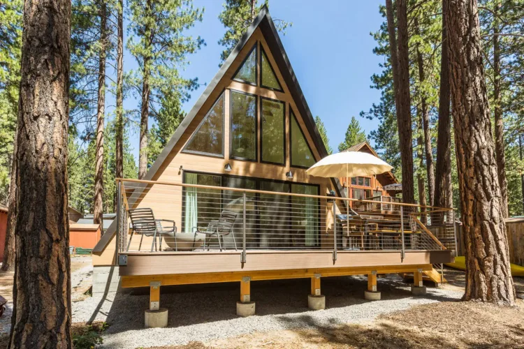 A modern Avrame Trio A-frame cabin with a large deck, an example of prefab home kits under 50k.