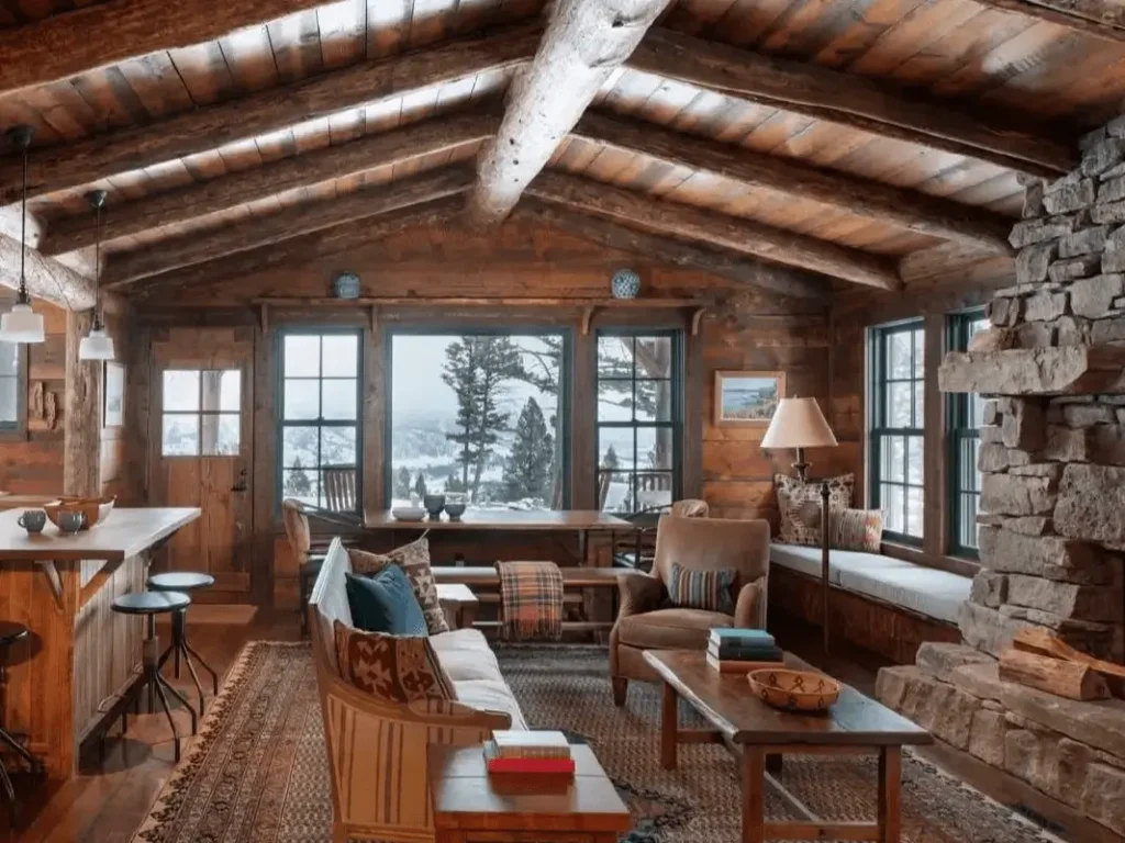 Cozy rustic cabin interior featuring an open-concept living, dining, and kitchen area with a stone fireplace.