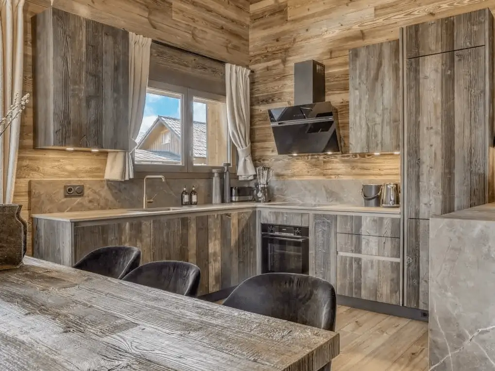 Modern rustic kitchen with weathered wood cabinets and gray marble-style countertops.