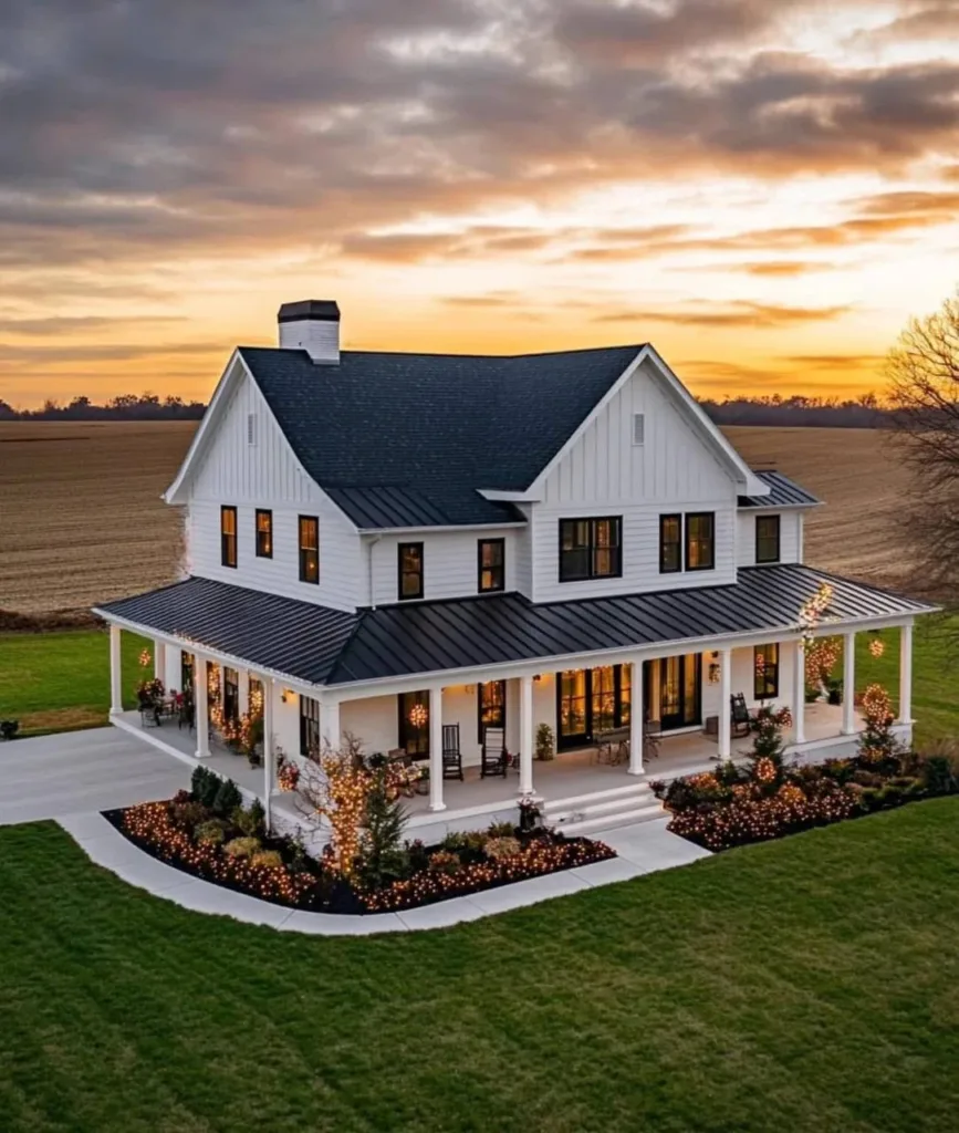 White farmhouse with a large wrap-around porch, black accents, and outdoor lighting