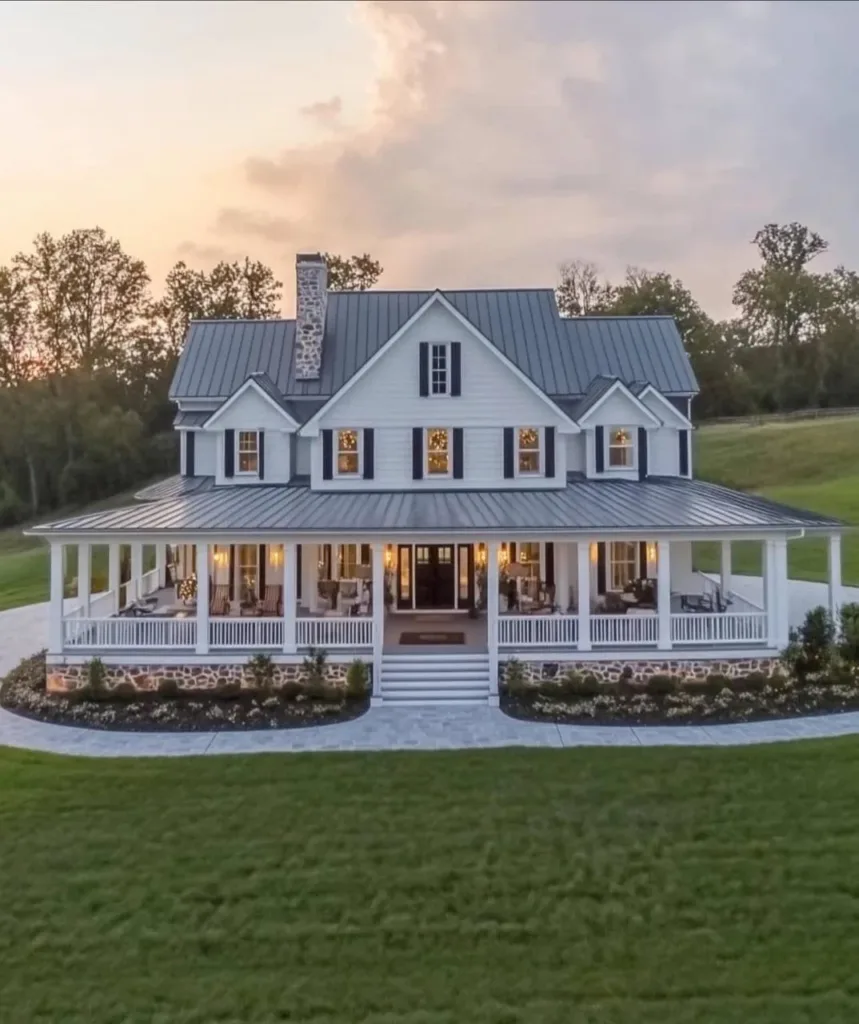 White farmhouse with a large, well-lit front porch and a stone walkway