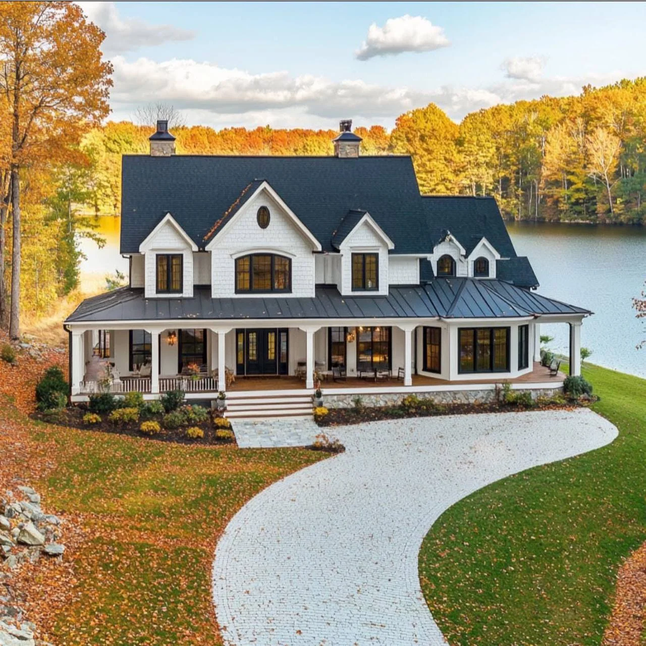 White farmhouse with a black roof, wrap-around porch, and a curved stone walkway.