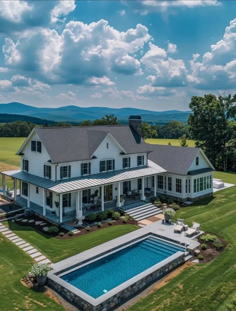 Aurora Farmhouse style home with a large backyard pool, wrap-around porch, and mountain views.