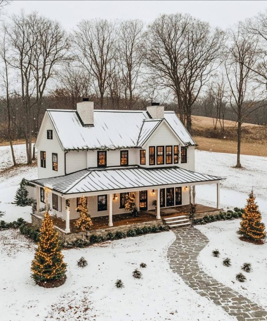 Modern farmhouse with a dark exterior, a metal roof, large windows, and a spacious patio with ample seating.