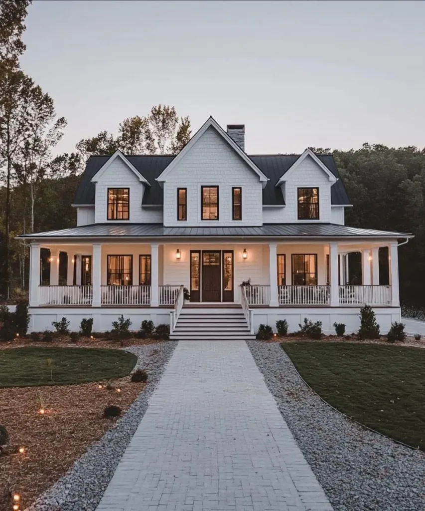 Modern farmhouse with white siding, a gray metal roof, black trim, and a large wrap-around porch, surrounded by an expansive front yard.