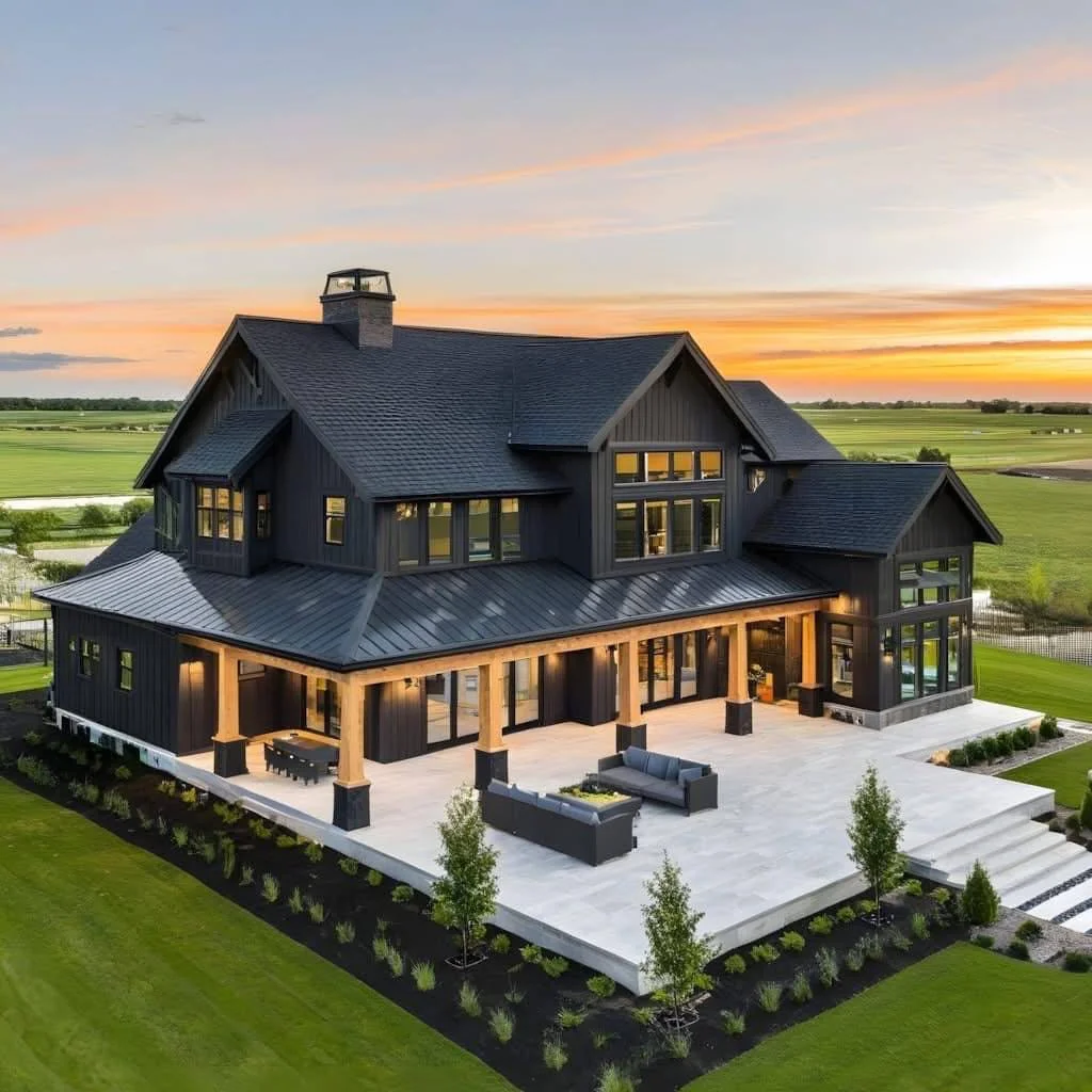 White farmhouse with a black roof, a gated entrance with stone pillars, surrounded by rolling hills and fall foliage.