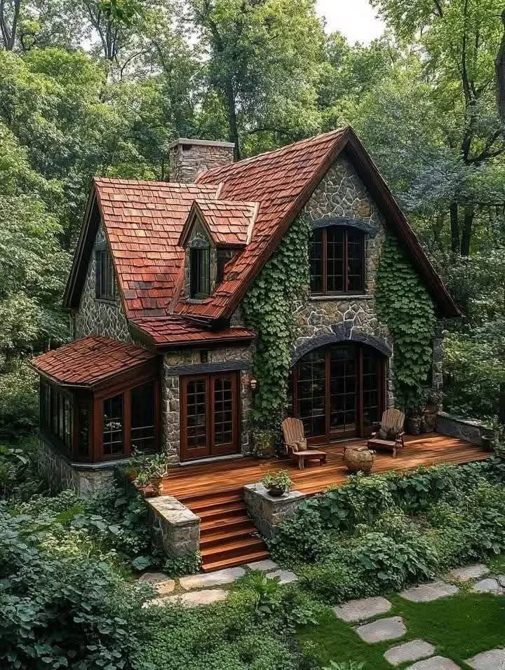 Fairy tale stone cottage with ivy and red roof.