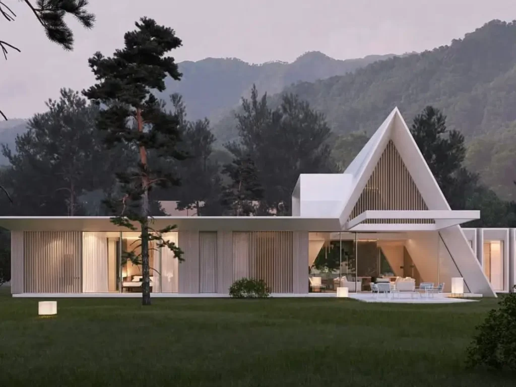 A modern white mountain house featuring a prominent A-frame design over the living space, with large glass walls opening to a lawn.