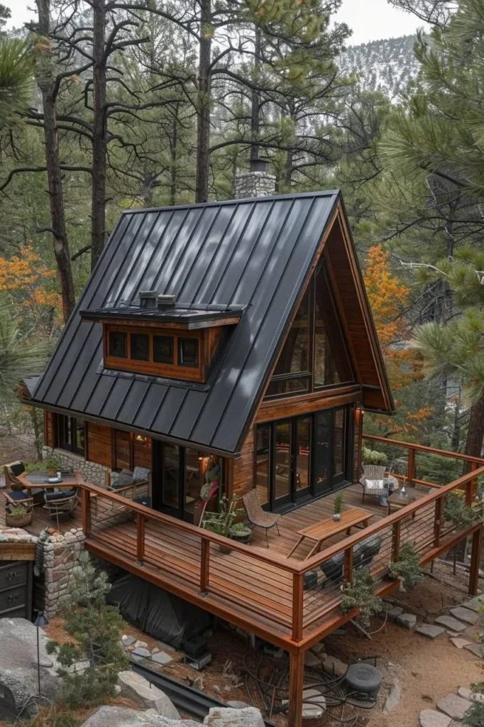 Modern A-frame cabin with a black roof and large deck, nestled in the woods for a stylish and peaceful retreat.