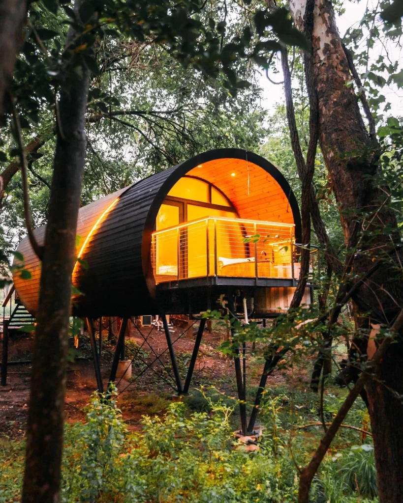 Dreamy cylindrical treehouse cabin with a balcony.