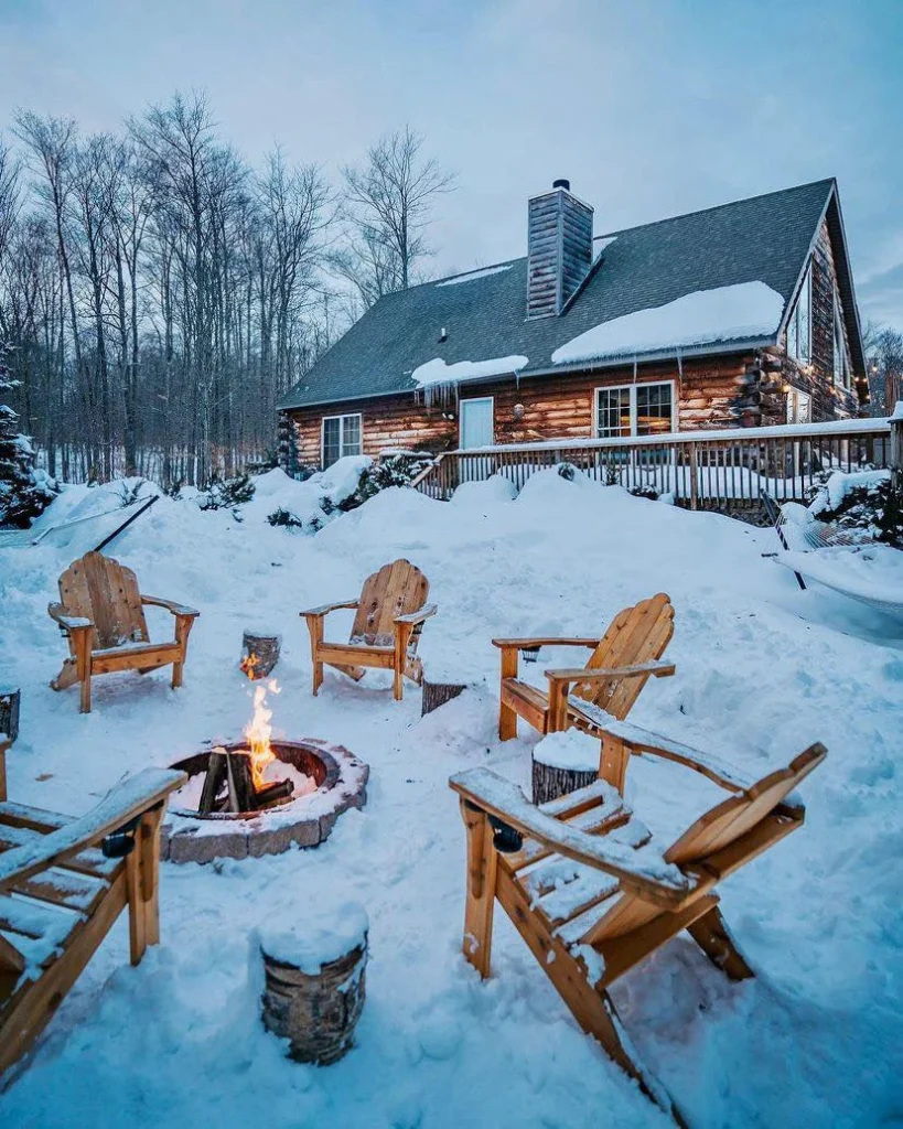 Dreamy log cabin in the snow with a fire pit and Adirondack chairs. Dreamy Cabin Getaways