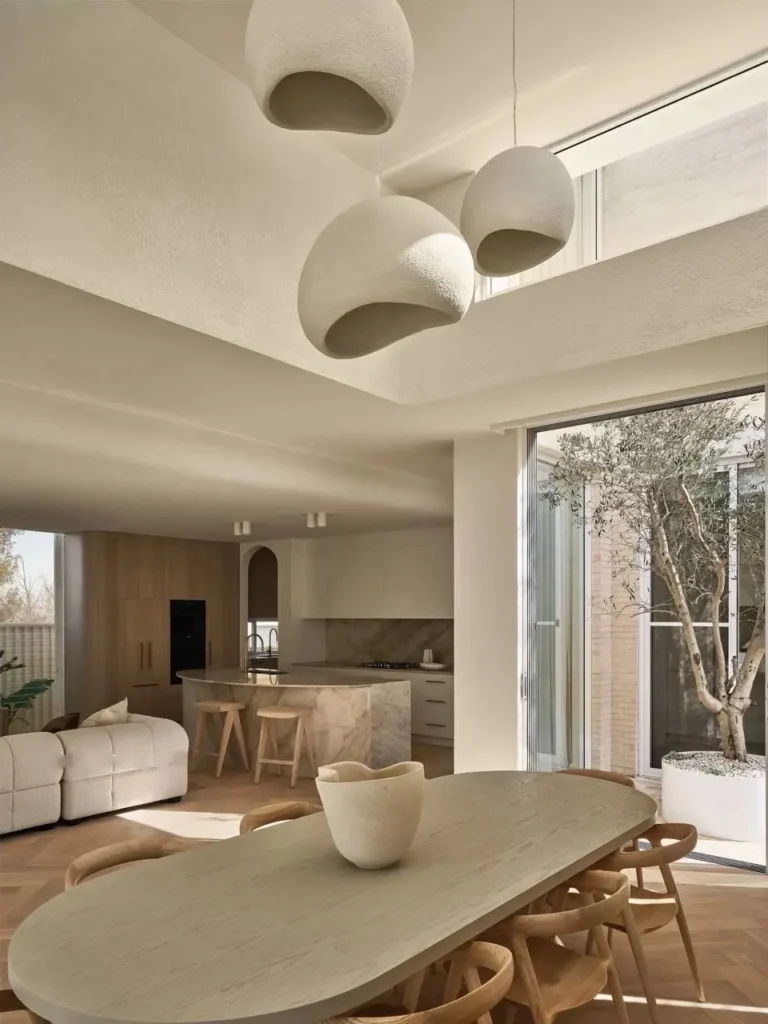 Spacious open-plan modern Mediterranean interior showing living, dining, and kitchen areas with natural light from courtyard.