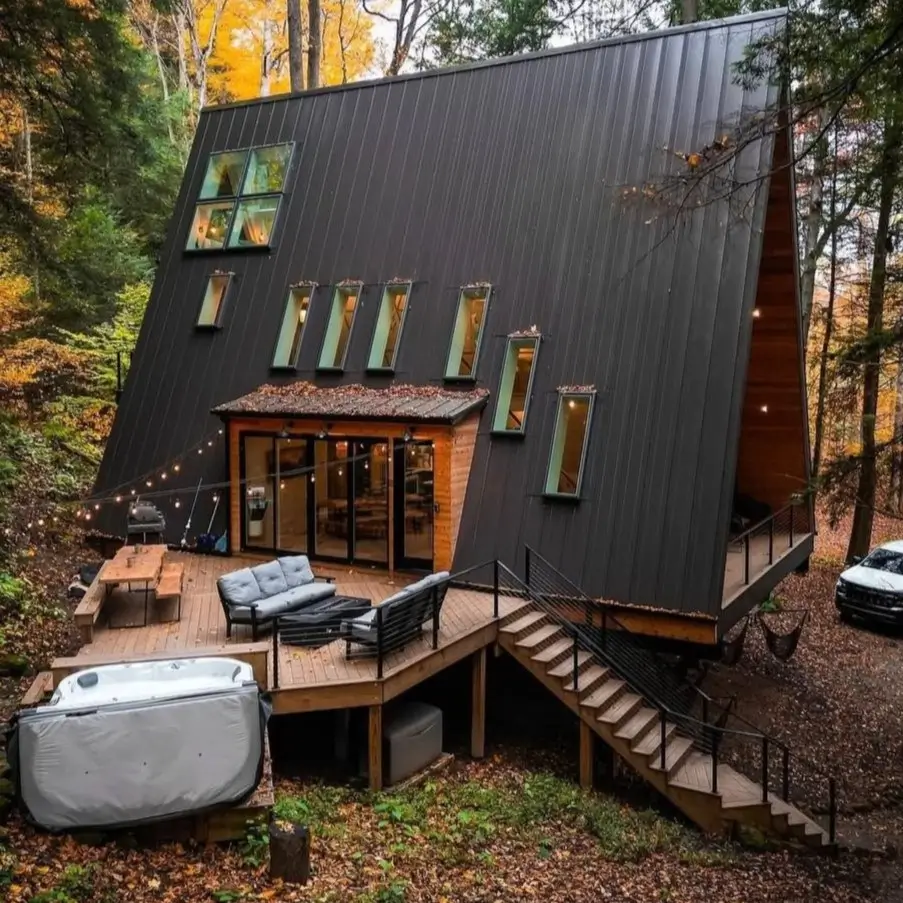 A modern black A-frame cabin nestled in the Hocking Hills woods with a spacious deck and hot tub.