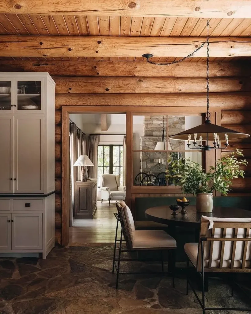 Cozy log cabin dining nook with round table and white cabinets.