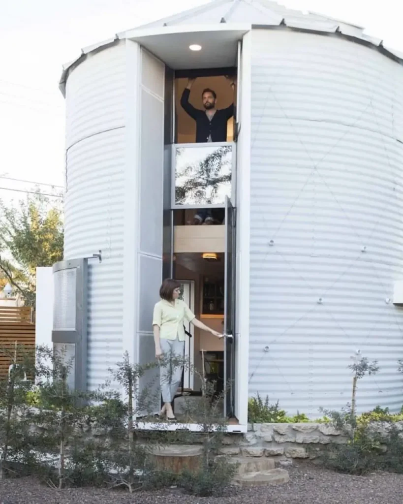 A modern, two-story tiny silo house with a recessed vertical entryway, showcasing both levels of the interior.