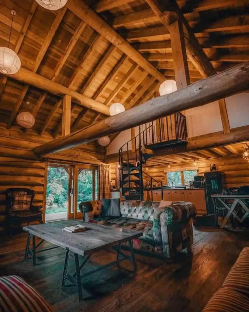 Spacious log cabin living area with high ceilings, exposed logs, and spiral staircase.