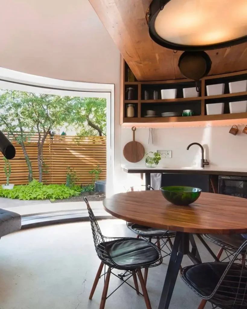 A view inside the tiny silo house kitchen and dining area, looking out through the curved glass door.