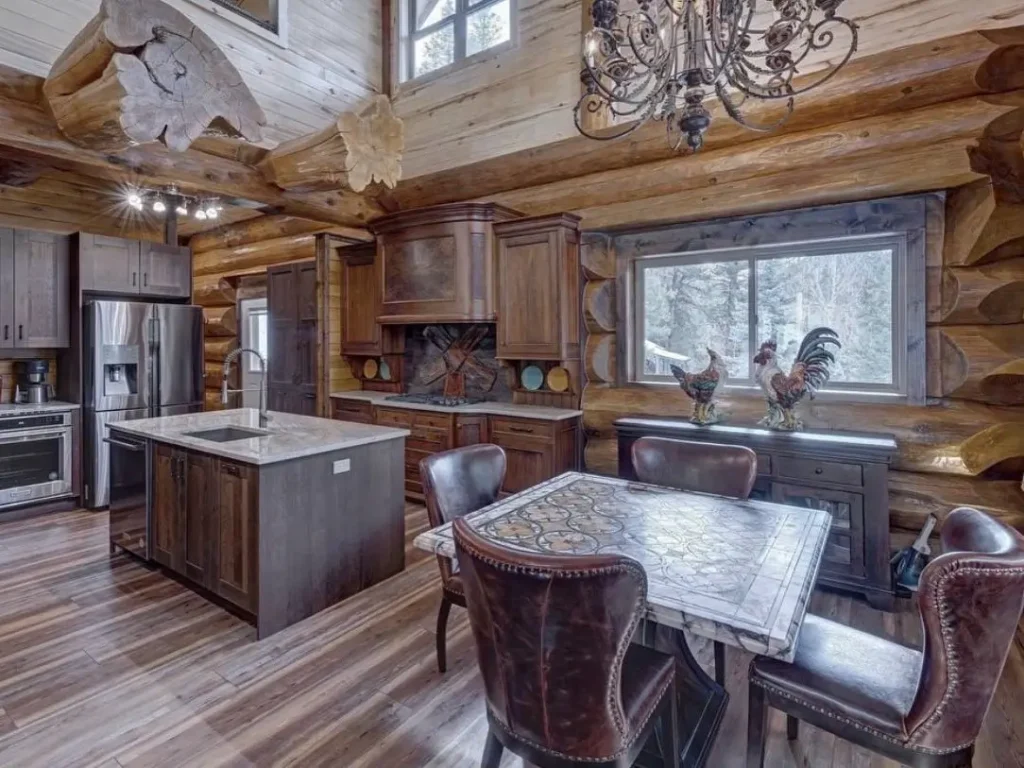 Grand log cabin kitchen with large wood beams and rustic cabinetry.